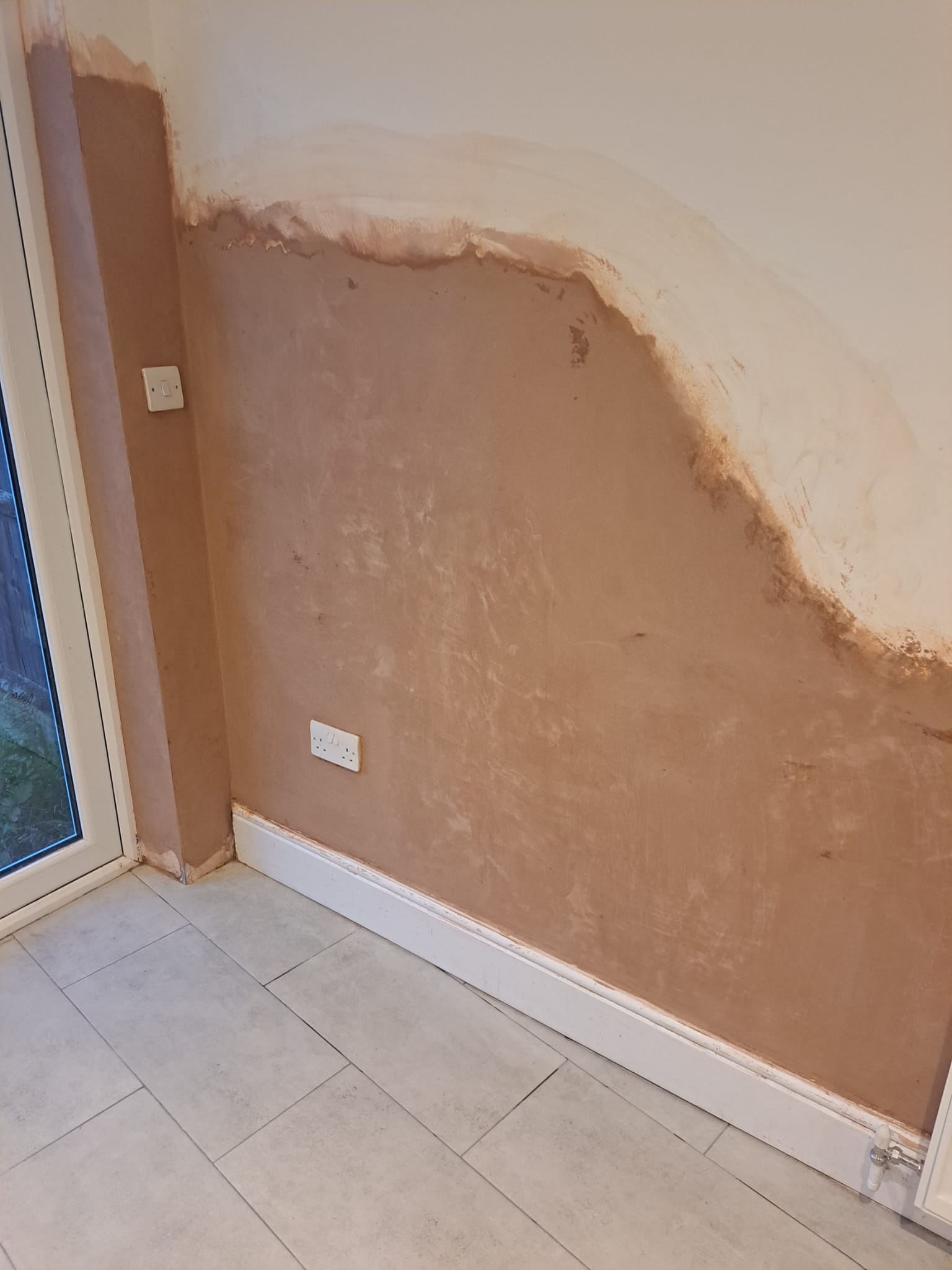 Wall beside the patio door freshly plastered and skimmed, ready for decoration